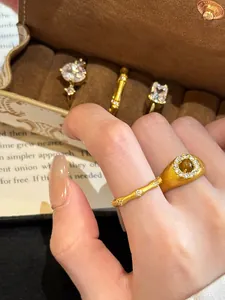 Macro view of a brushed gold bamboo joint ring with zircon accents on a model's finger.
