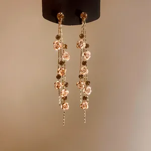 Detailed view of long tassel earrings with delicate pink roses and sparkling crystals