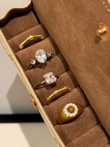 Detailed view of various brushed gold rings with zircons set in a premium velvet box