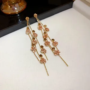 Elegant long tassel earrings with rose flower and rhinestone details on white background