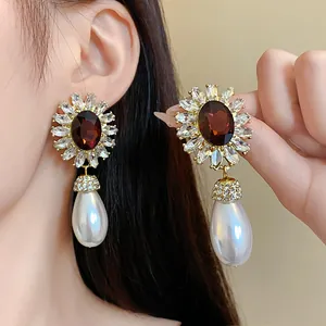 Détail de boucles d'oreilles fleurs vintage françaises avec cristal brun et perle poire