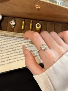 Detailed view of a vintage gold ring featuring a sparkling square zircon on a model's hand.