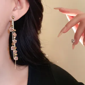 Close-up detail of elegant long tassel earrings with rose flower motifs and rhinestones