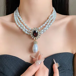 Vue détaillée d'un collier de perles à trois rangs avec pendentif fleur serti de pierres