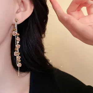 Close-up of elegant long tassel earrings featuring rose flower and sparkly rhinestone details
