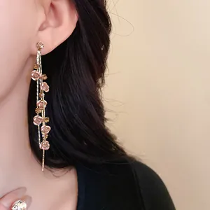 Detail view of elegant rose flower tassel earrings with rhinestones on model's ear