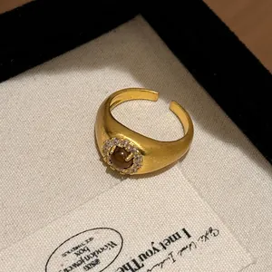 Detailed view of a vintage brushed gold open ring with a brown stone and zircon halo.