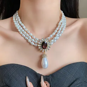 Détail d'un collier de perles à trois rangs de style palais français avec pendentif.