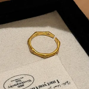 Close-up detail of vintage brushed gold bamboo-knot open ring with zircon stones