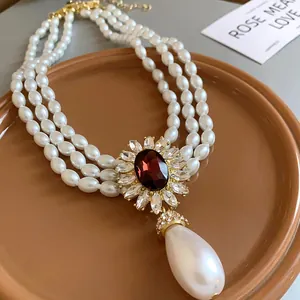 Détail d'un collier de perles à trois rangs avec pendentif fleur vintage et perle goutte