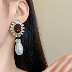 Détail d'une boucle d'oreille fleurie de style vintage avec perle goutte et pierre.