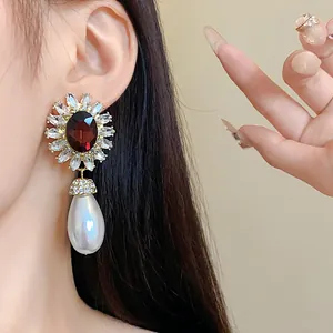 Détail de boucle d'oreille fleurie vintage avec pierre rouge et perle en goutte