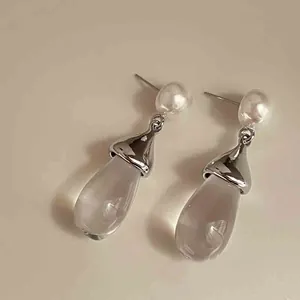 Primer plano de elegantes pendientes de resina con perlas blancas y detalles plateados
