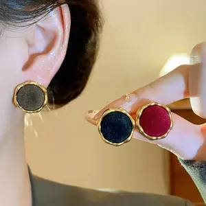 Detalle de elegantes pendientes redondos con bordes dorados y centros flocados suaves.