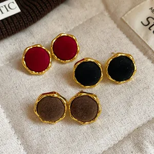 Detalle de elegantes pendientes de botón redondos flocados en tres colores vintage distintos.