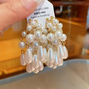 Macro view of elegant silver needle earrings with multi-layer teardrop pearl tassels