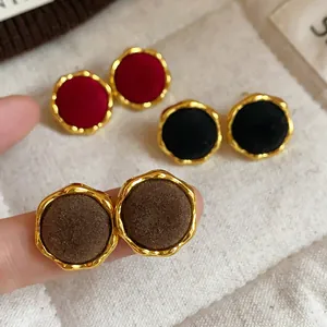 Primer plano de elegantes pendientes flocados en burdeos, negro y marrón con marcos dorados
