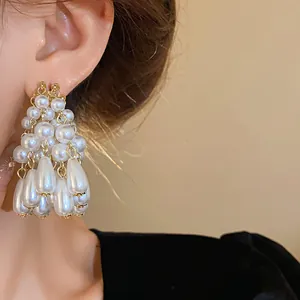 Macro close-up detail of elegant white waterdrop pearl tassel earrings on a model's ear