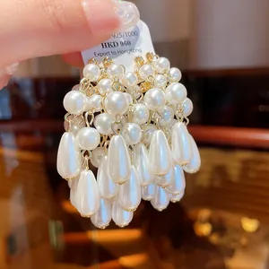 Detailed macro view of elegant white teardrop pearl tassel earrings with silver needles