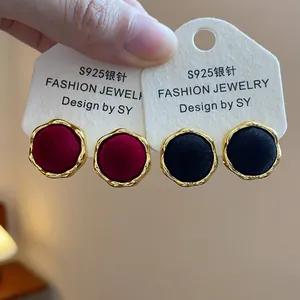 Detalle de elegantes pendientes de botón redondos flocados en rojo y negro con agujas de S925