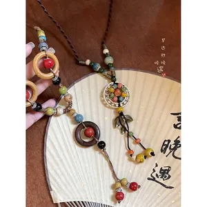Dettaglio di una collana etnica bohémien intrecciata con perle di ceramica e anelli di legno