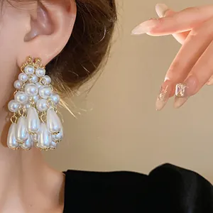 Close-up of elegant waterdrop pearl tassel earrings worn on ear showing fine details.