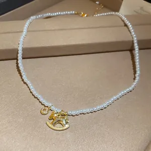 Macro view of a zircon rocking horse pendant on a vintage-style white pearl necklace.
