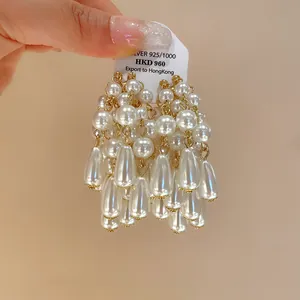 Detailed macro shot of elegant white drop pearl tassel earrings in gold setting