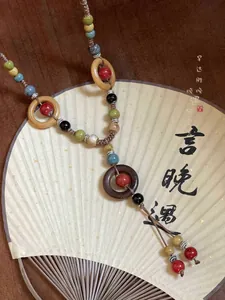 Vista dettagliata della collana in ceramica bohémien con anelli in legno e corda marrone