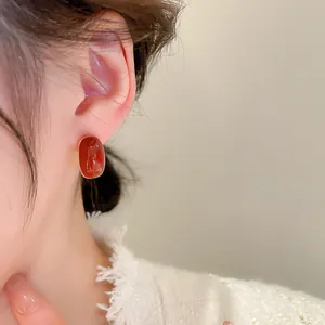 Gros plan de boucles d'oreilles élégantes en pierre ovale rouge portées par le modèle