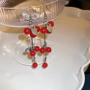 Détail de boucles d'oreilles vintage à pampilles de baies rouges sur un plat en verre