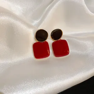 Détail de boucles d'oreilles carrées rouges vintage sur soie blanche