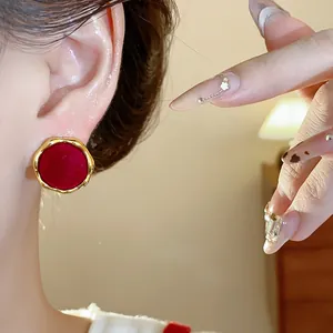 Primer plano de elegantes pendientes redondos de terciopelo rojo con borde dorado