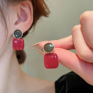 Détail de boucles d'oreilles carrées rouges vintage avec bord doré et design élégant