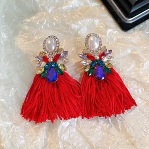 Vue détaillée de boucles d'oreilles à pompons rouges avec cristaux colorés et perles.