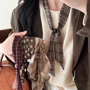 Detailed view of various retro plaid and floral silk scarf necklaces worn with a brown blazer