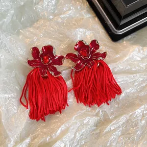 Vue détaillée de boucles d'oreilles fleur en émail rouge avec de longues franges