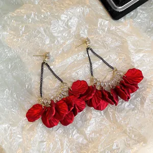 Vue détaillée des boucles d'oreilles pétales rouges avec chaînes noires et clous en cristal