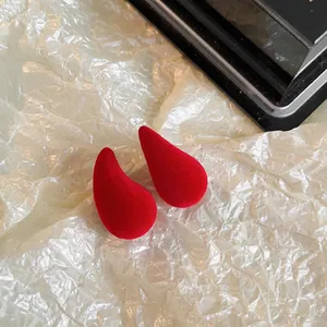 Gros plan de boucles d'oreilles en velours rouge en forme de goutte sur papier doré