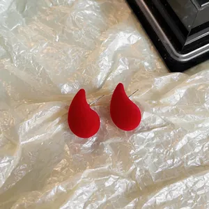 Vue détaillée de boucles d'oreilles clous goutte en velours rouge avec tiges argent