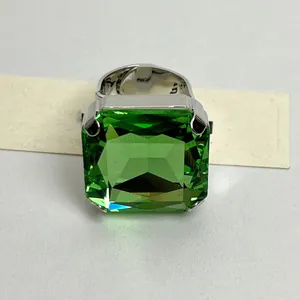Primo piano di un anello con grande gemma quadrata verde e fascia argentata