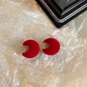 Gros plan de boucles d'oreilles croissant de lune en velours rouge.