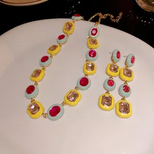 Farbenfrohes geometrisches Schmuckset mit Emaille und Strasssteinen auf weißem Teller