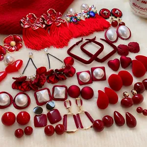 Collection de boucles d'oreilles rouges festives aux motifs de fleurs, pompons et cœurs.