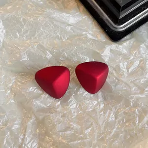 Gros plan de boucles d'oreilles triangulaires rouge mat avec aiguilles en argent