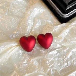Vue détaillée de la finition mate des boucles d'oreilles cœur rouge sur papier