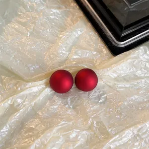 Vue macro détaillée d'élégantes boucles d'oreilles sphériques rouge mat sur fond texturé