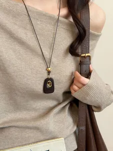 Close-up of vintage resin necklace with tiger eye stone worn on a beige sweater