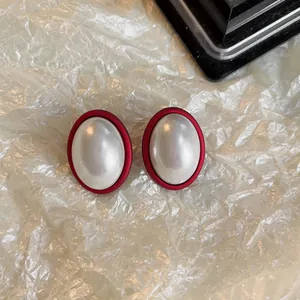 Gros plan de boucles d'oreilles ovales rouges vintage avec un centre perlé élégant