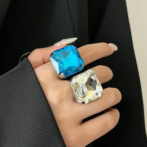 Vista dettagliata di grandi anelli aperti in cristallo quadrato blu e champagne da donna